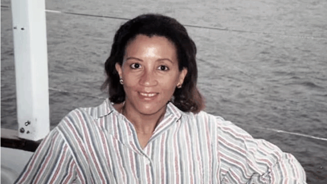 Zandra I. Flemister on the Connecticut River, 1997. She smiles on a boat, wearing a white shirt with black stripes.