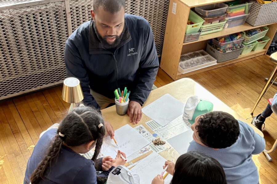 BARI Team member sits at a table with three young children and they work together on graphs and charts.