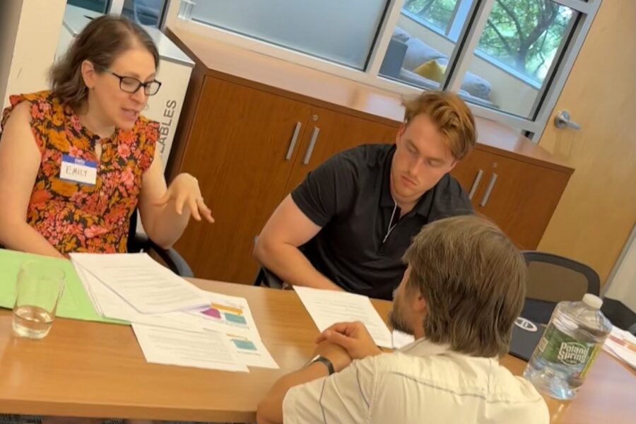 Three people huddling around table in conversation.