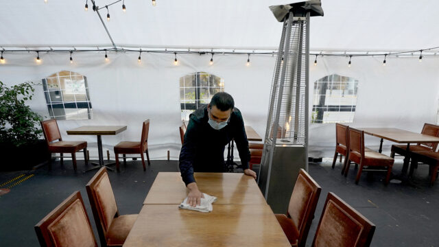 Fabian Rodriguez cleans a table in an outdoor tented dining area of Tequila Museo Mayahuel restaurant, in Sacramento, Calif., Thursday, Nov. 19, 2020.