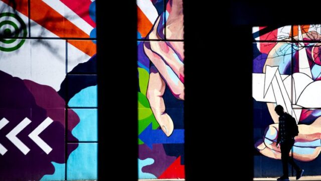 silhouette of a person framed by a triptych of a mural