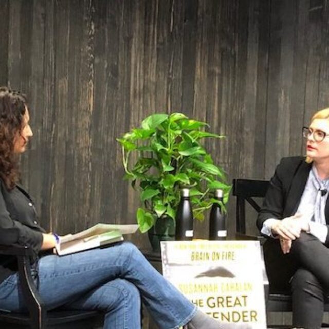 Susannah Cahalan (right) speaks with a seated woman at a table.