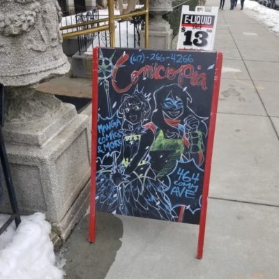 a sidewalk sign at Comicopia featuring drawings made in chalk