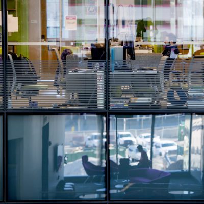 View of the labs in ISEC: tables and chairs surrounding desks and a student working at one computer