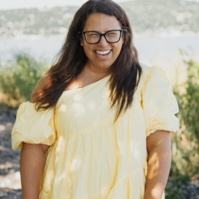 Dayna Altman in a yellow dress smiling at the camera lens.