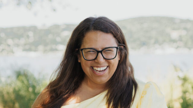 Dayna Altman in a yellow dress smiling at the camera lens.