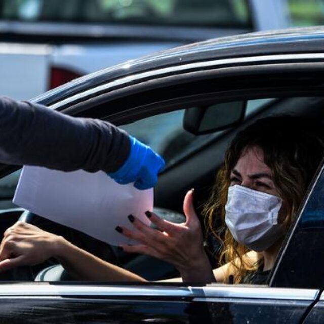 A woman collects unemployment forms at a drive through collection point outside John F. Kennedy Library in Hialeah, Florida, on April 8, 2020.