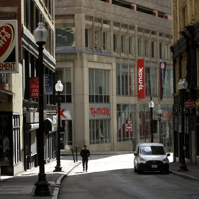 A passerby walks along a nearly empty street in the Downtown Crossing neighborhood of Boston