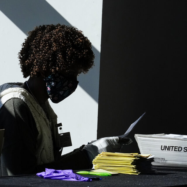 An election worker handles ballots as vote counting in the general election continues at State Farm Arena on Wednesday, Nov. 4, 2020, in Atlanta.