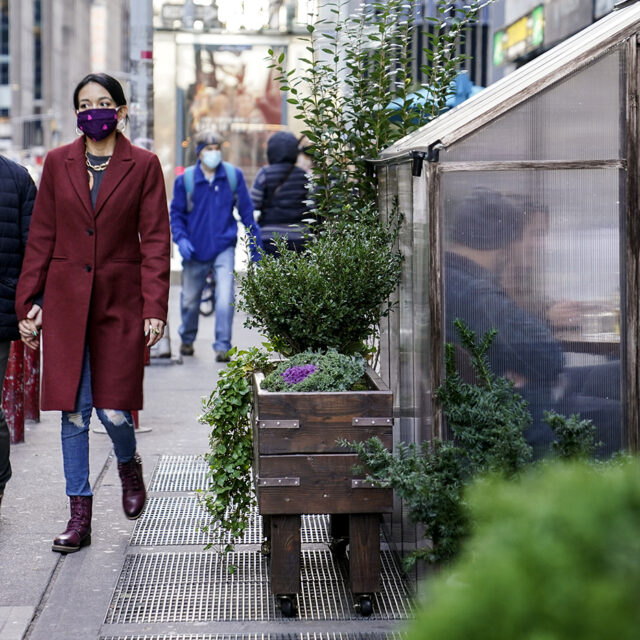 Diners sit inside a semi-transparent sidewalk housing at a restaurant while observing social distancing protocols to combat the spread of COVID-19