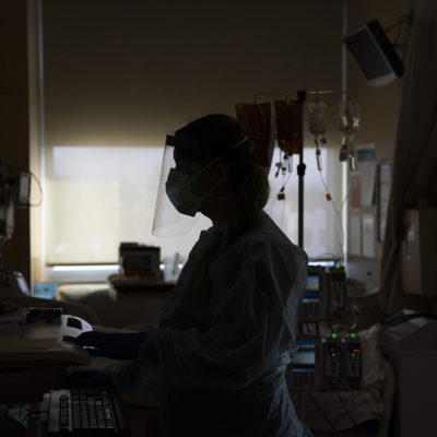 In this Nov. 19, 2020, file photo, registered nurse Virginia Petersen works on a computer while assisting a COVID-19 patient at Providence Holy Cross Medical Center in the Mission Hills section of Los Angeles.