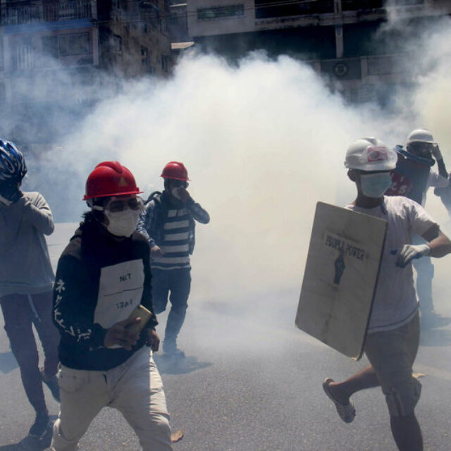 Anti-coup protesters run away from tear gas launched by security forces in Yangon, Myanmar, Monday, March 1, 2021.