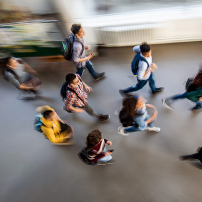 High angle view of large group of students running through the school hallway. Blurred motion.