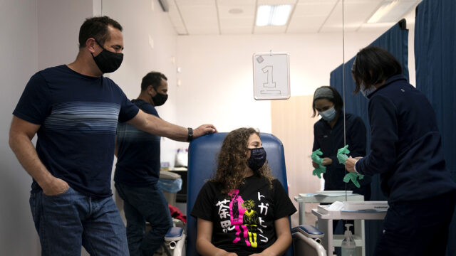 Sarah Jackman, 12, center, waits to receive the Pfizer COVID-19 vaccine from nurse practitioner Nicole Noche, right, as she is accompanied by her father, Scott, at Families Together of Orange County in Tustin, Calif., Thursday, May 13, 2021.