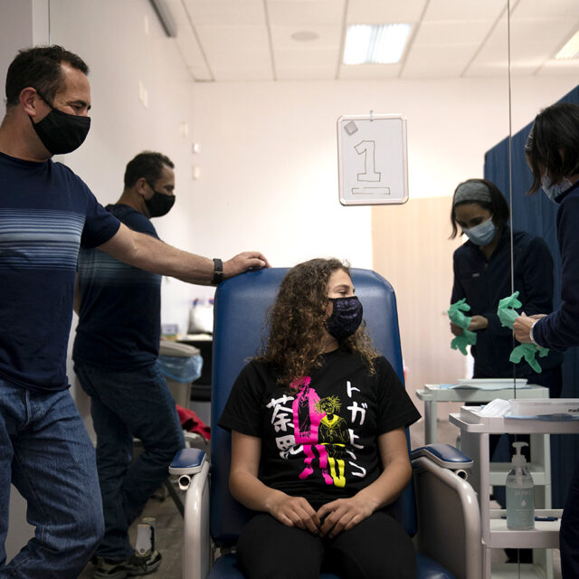 Sarah Jackman, 12, center, waits to receive the Pfizer COVID-19 vaccine from nurse practitioner Nicole Noche, right, as she is accompanied by her father, Scott, at Families Together of Orange County in Tustin, Calif., Thursday, May 13, 2021.
