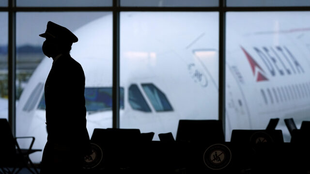 a Delta Airlines pilot wears a face mask to help prevent the spread of the new coronavirus as he walks through a terminal at Hartsfield-Jackson International Airport in Atlanta.