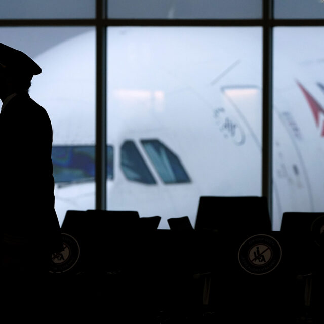 a Delta Airlines pilot wears a face mask to help prevent the spread of the new coronavirus as he walks through a terminal at Hartsfield-Jackson International Airport in Atlanta.