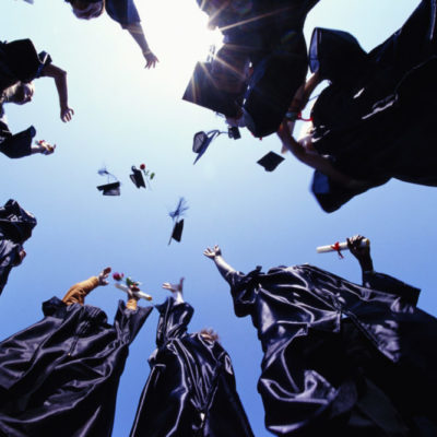 Worms eye view of recent graduates throwing their graduation caps in the air.