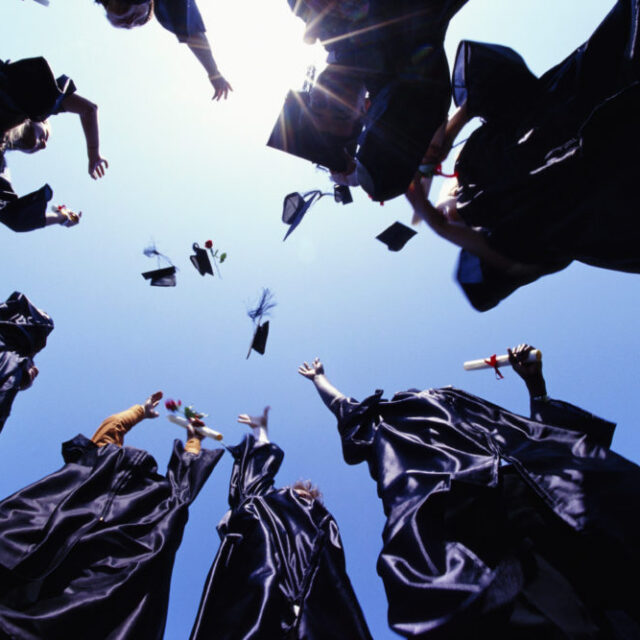 Worms eye view of recent graduates throwing their graduation caps in the air.