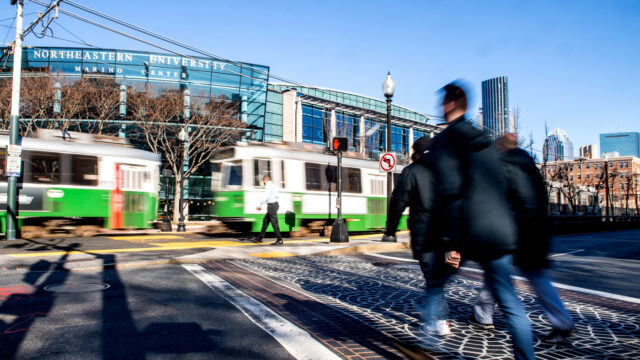 01/25/21 - BOSTON, MA - Members of the Northeastern community cross Huntington Avenue behind a Green Line train on Jan. 25, 2021.