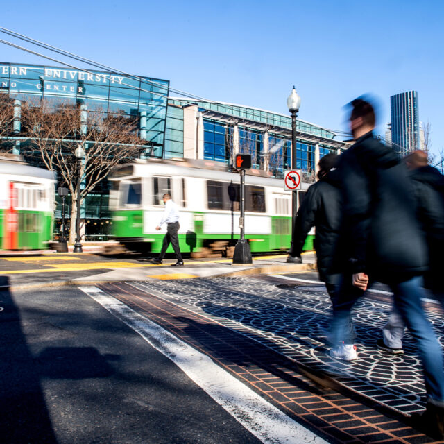 01/25/21 - BOSTON, MA - Members of the Northeastern community cross Huntington Avenue behind a Green Line train on Jan. 25, 2021.