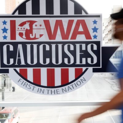 A pedestrian walks past a sign for the Iowa Caucuses on a downtown skywalk, in Des Moines, Iowa, on Feb. 4, 2020.