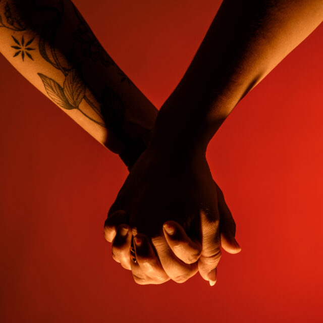 Two hands holding in front of a red background.