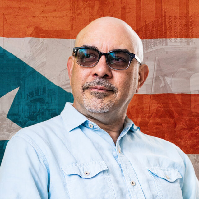 Headshot of Amílcar Antonio Barreto in front of the Puerto Rican flag.