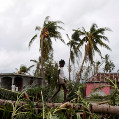 A young girl walks on a fallen tree in Haiti after Hurricane Matthew made landfall in 2016.
