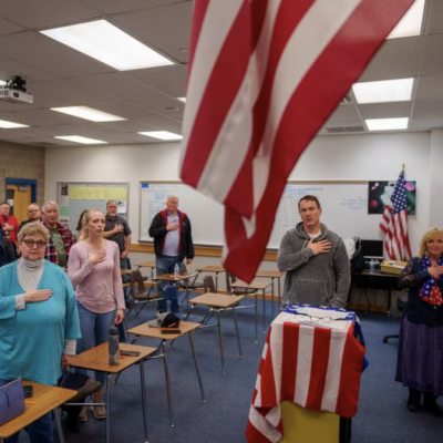 People in a classroom standing up for the Pledge of Allegiance.