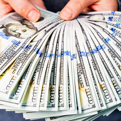 A woman holds a lot of hundred dollar bills in her hands. Without a face. Close-up from a low angle.