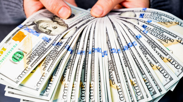 A woman holds a lot of hundred dollar bills in her hands. Without a face. Close-up from a low angle.