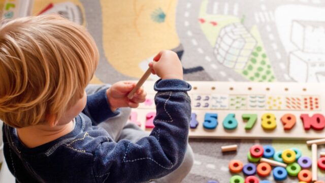 Small toddler playing with alphabet toys.