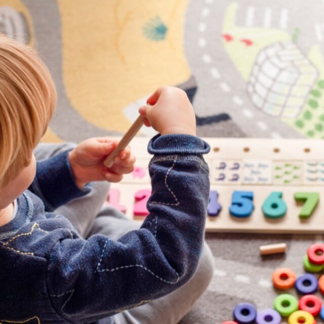 Small toddler playing with alphabet toys.