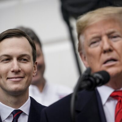 Jared Kushner(left) smiling as Donald Trump (right) speaks.