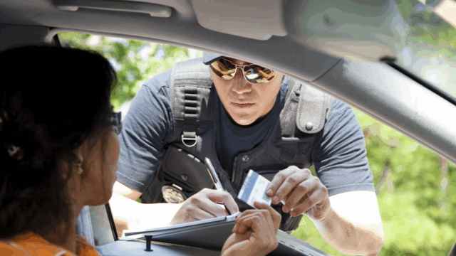 Policeman stops woman driver to give her a traffic ticket for speeding. He takes her driver's license.
