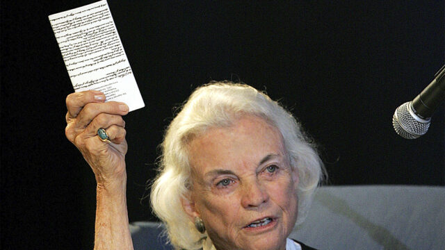 U.S. Supreme Court Justice Sandra Day O'Connor hold up a copy of the U.S. constitution that she carries with her Saturday, Sept. 17, 2005 at an open-air Immigration and Naturalization citizenship hearing in Gilbert, Ariz.