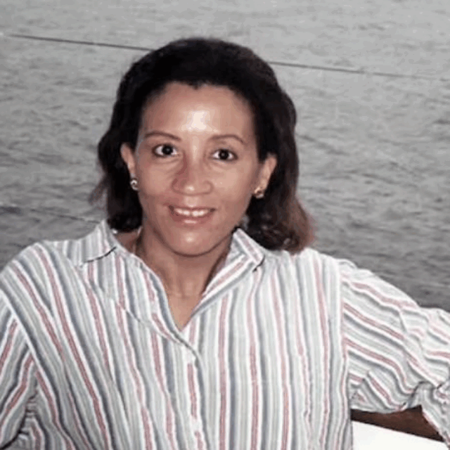 Zandra I. Flemister on the Connecticut River, 1997. She smiles on a boat, wearing a white shirt with black stripes.