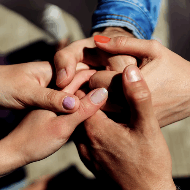 Three people hold hands together under sunlight. Image comes with text: Interest in polyamory has taken the media by storm in recent weeks. Data shows that acceptance of non-traditional family structures is on the rise. Photo by Getty Images