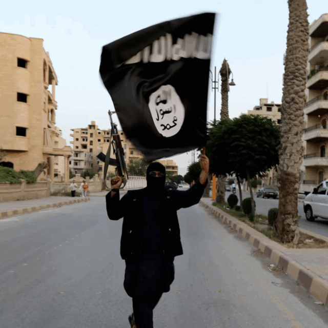 image of ISIS-K member in the street holding up a flag of ISIS