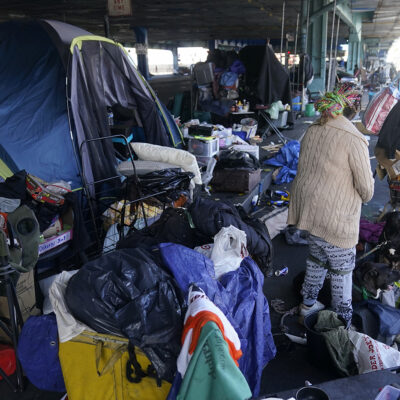 image of woman gathering possessions to take before a homeless encampment was cleaned up in San Francisco on Aug. 29, 2023