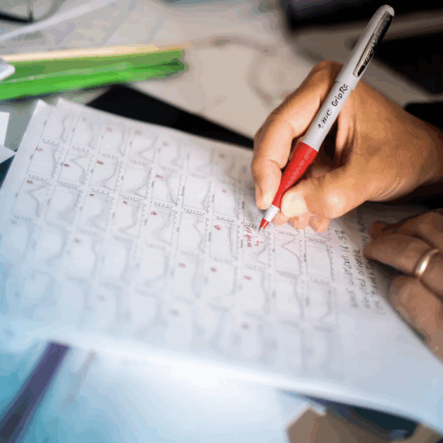 image of hand holding red pen writing on a paper of scientific report