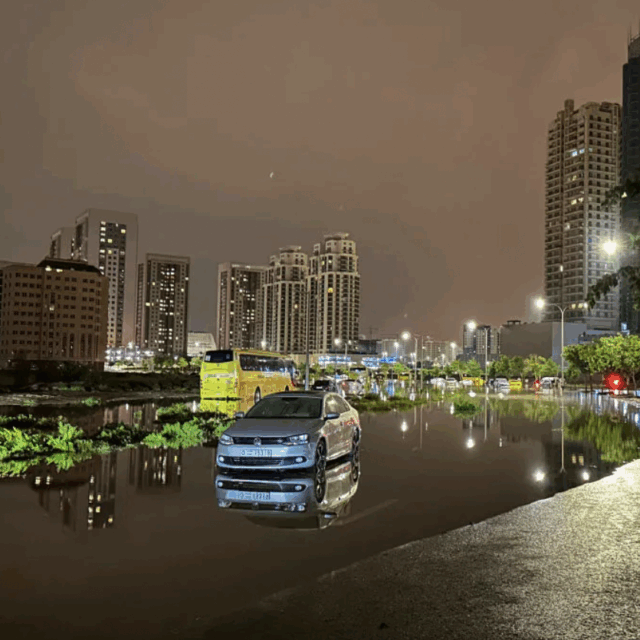 image of car in deep water in front of skyline due to flooding