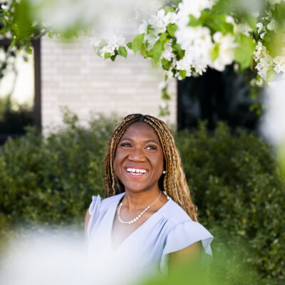 image of 2024 undergrad commencement speaker rebecca bamidele with white flowers in frame blurred