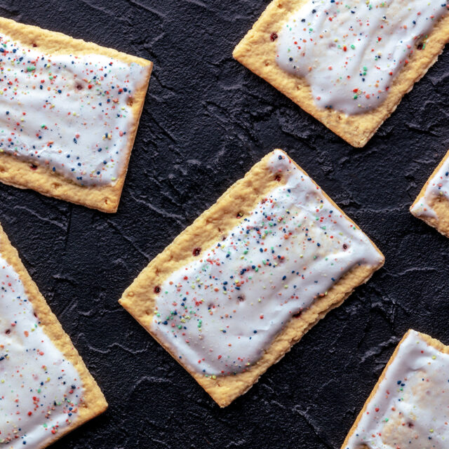 Pop tarts layout. Poptart toaster pastry with icing on a black slate background, overhead flat lay shot.