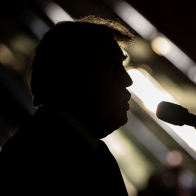 image of trump behind shadow speaking into microphone