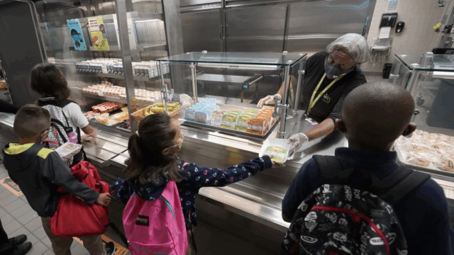Food service assistant Brenda Bartee, rear, gives students breakfast at Washington Elementary School in Riviera Beach, Fla., iin August, 2021.