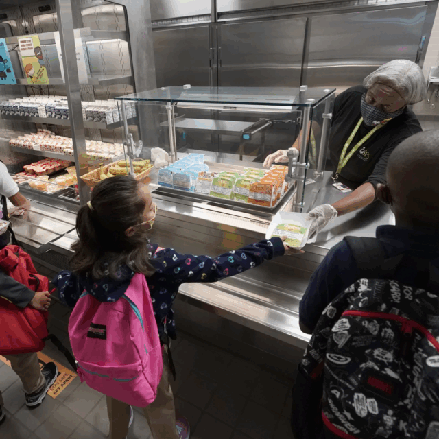 Food service assistant Brenda Bartee, rear, gives students breakfast at Washington Elementary School in Riviera Beach, Fla., iin August, 2021.