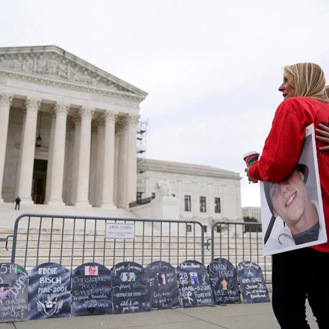 Women with photos of loved ones who died from using Oxycontin.