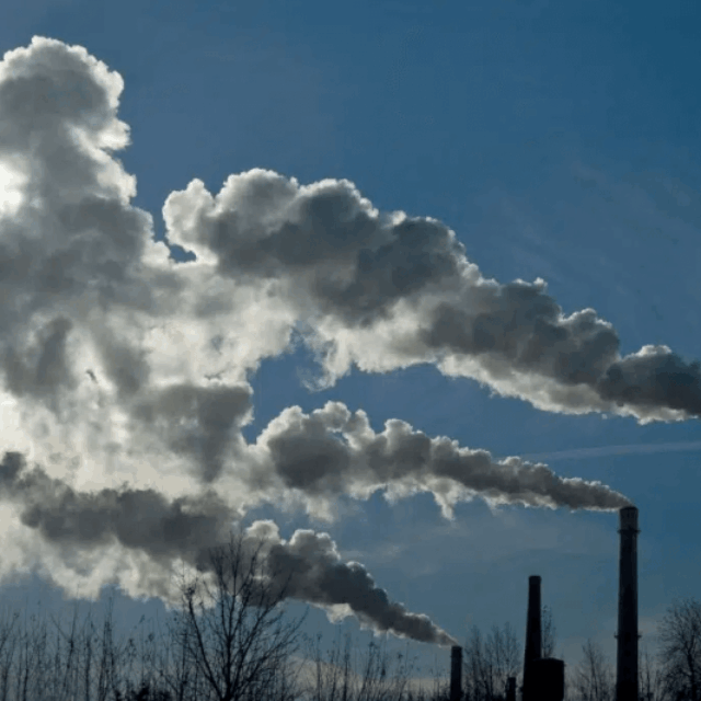 Smoke stacks releasing smoke into the atmosphere. (Earth.org)
